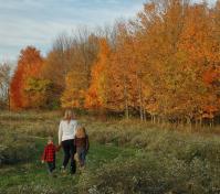 woman and two children walking on a path in the fall