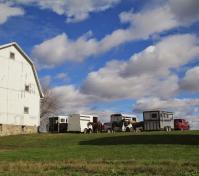 large view of blue sky, barn and horse trailers